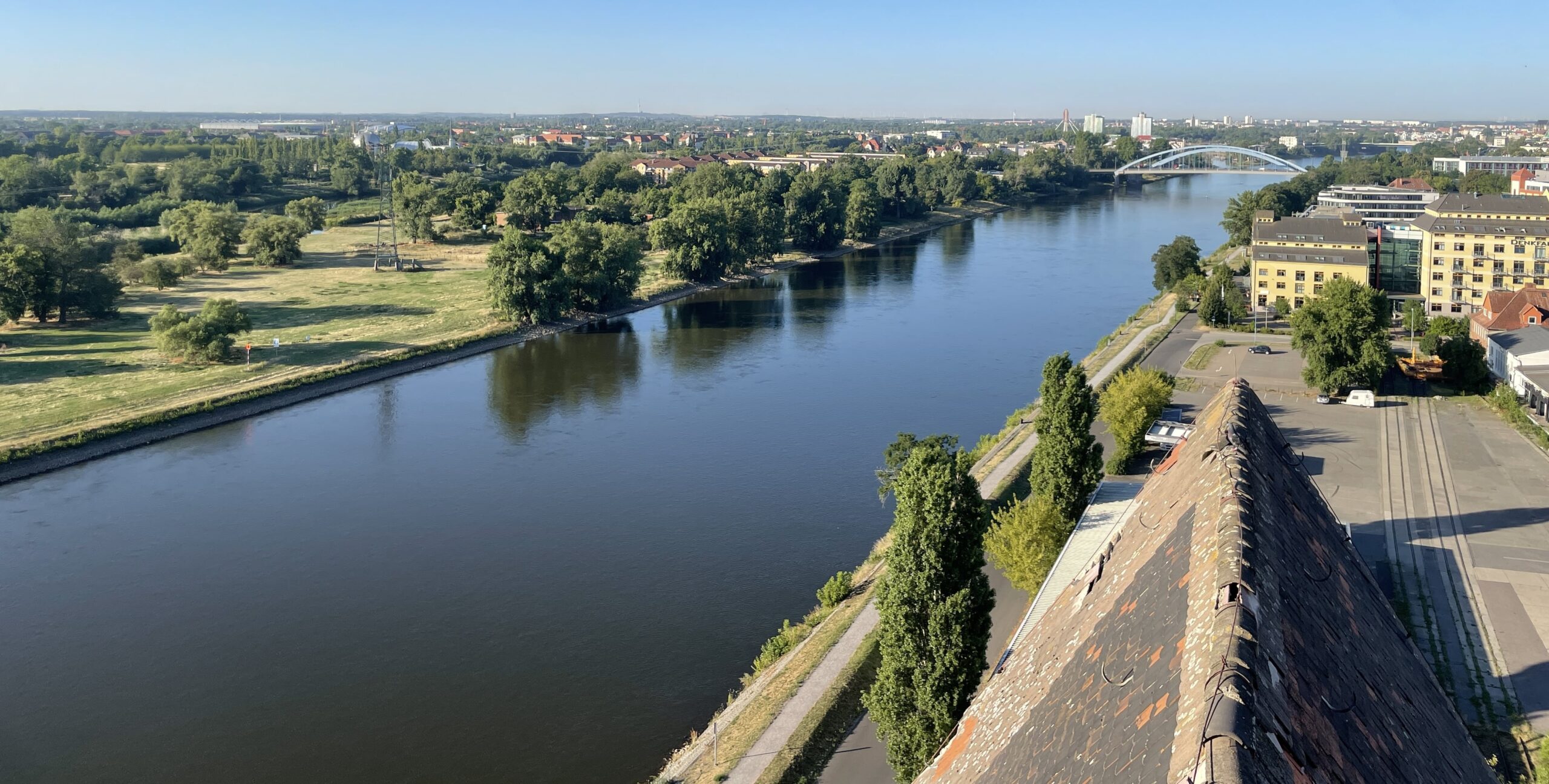 Blick auf Fluss mit Ufer, Bäumen und Gebäuden.