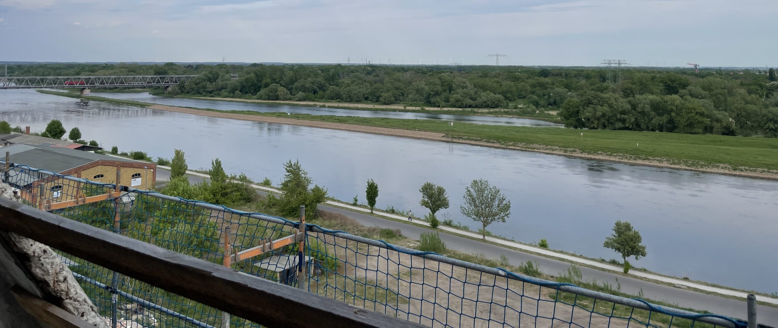 Blick auf Fluss, Brücke und grüne Landschaft.