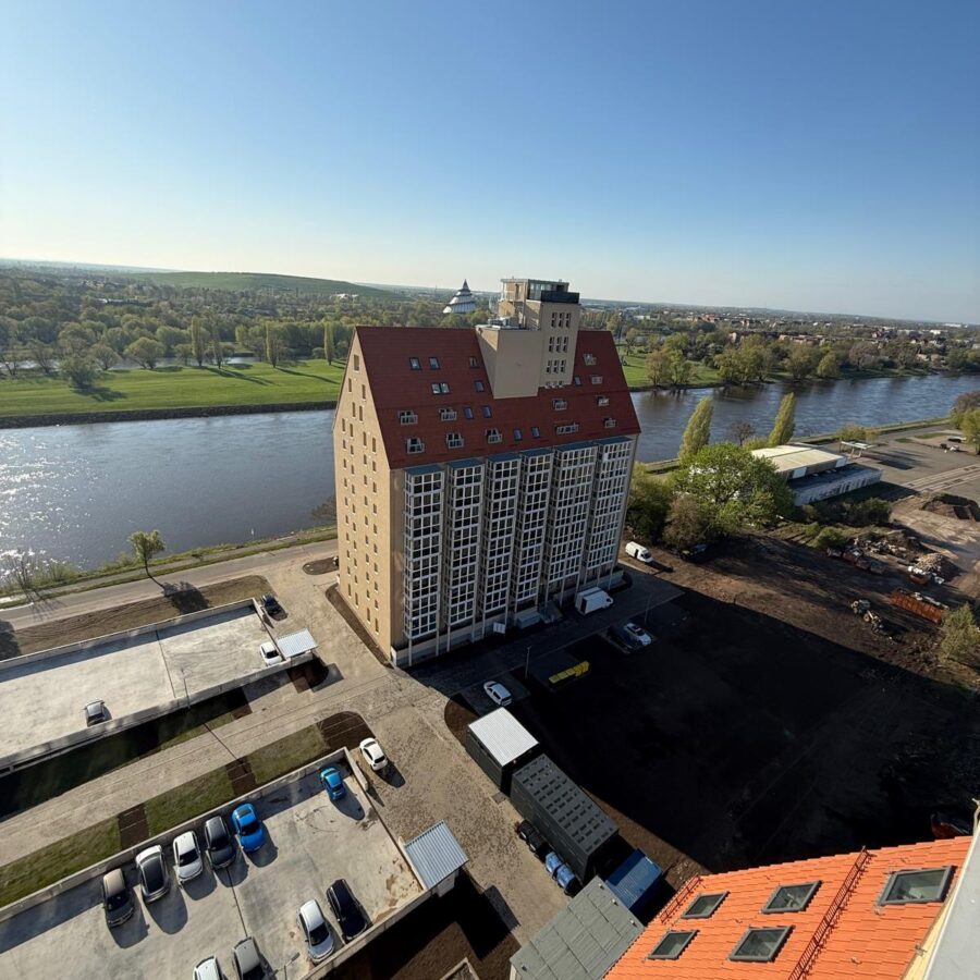 Blick auf modernes Gebäude Silo A an der Elbe, umgeben von grüner Landschaft und klarem Himmel.