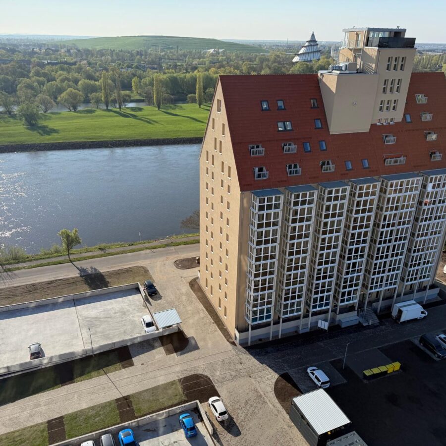 Silo A an der Elbe, umgeben von grüner Landschaft und strahlendem Sonnenschein.